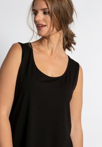 Schwarzes ärmelloses Top aus weichem Stoff, mit rundem Ausschnitt und lockerem Schnitt, mit glatter Textur.