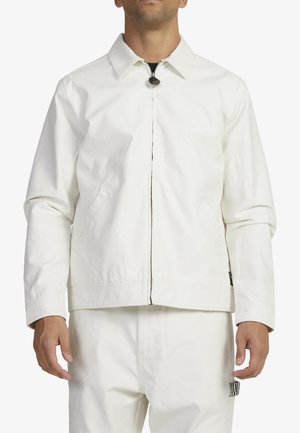 White cotton jacket with a collar, zip front, and patch pockets. Features a straight cut with clean lines and minimalistic design.