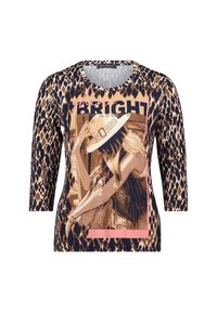 Bluzka w panterkę z rękawami 3/4, z grafiką przedstawiającą kobietę w kapeluszu. Kolory to brązowy, beżowy oraz różowe akcenty.