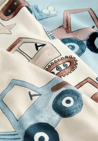 Stoff mit Illustrationen von bunten Traktoren und Zahnrädern. Strukturiert mit Pastelltönen in Blau, Creme und Braun.