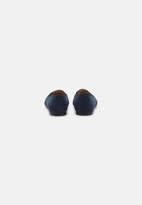 Mocassini in suede blu navy con suola bassa in gomma nera e punta a mandorla. Tessuto morbido senza motivi visibili o dettagli in metallo.