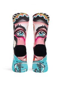 Bunte Socken mit einem Design, das ein Gesicht zeigt, blauen Akzenten, schwarzen Zehen und lebhaften Mustern auf einem hellblauen Hintergrund.