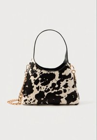Black and white cow-print handbag with a curved handle, gold chain accent, and a smooth texture. Features a structured shape and contrast trim.