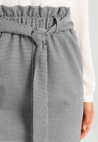 Gonna a vita alta in tessuto a scacchi bianco e nero, con una vita arricciata e un tessuto con texture.