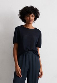 Marineblauwe t-shirt met korte mouwen van een lichtgewicht materiaal, met een relaxte pasvorm en een ronde halslijn, gecombineerd met donkergrijze broek met elastische taille.