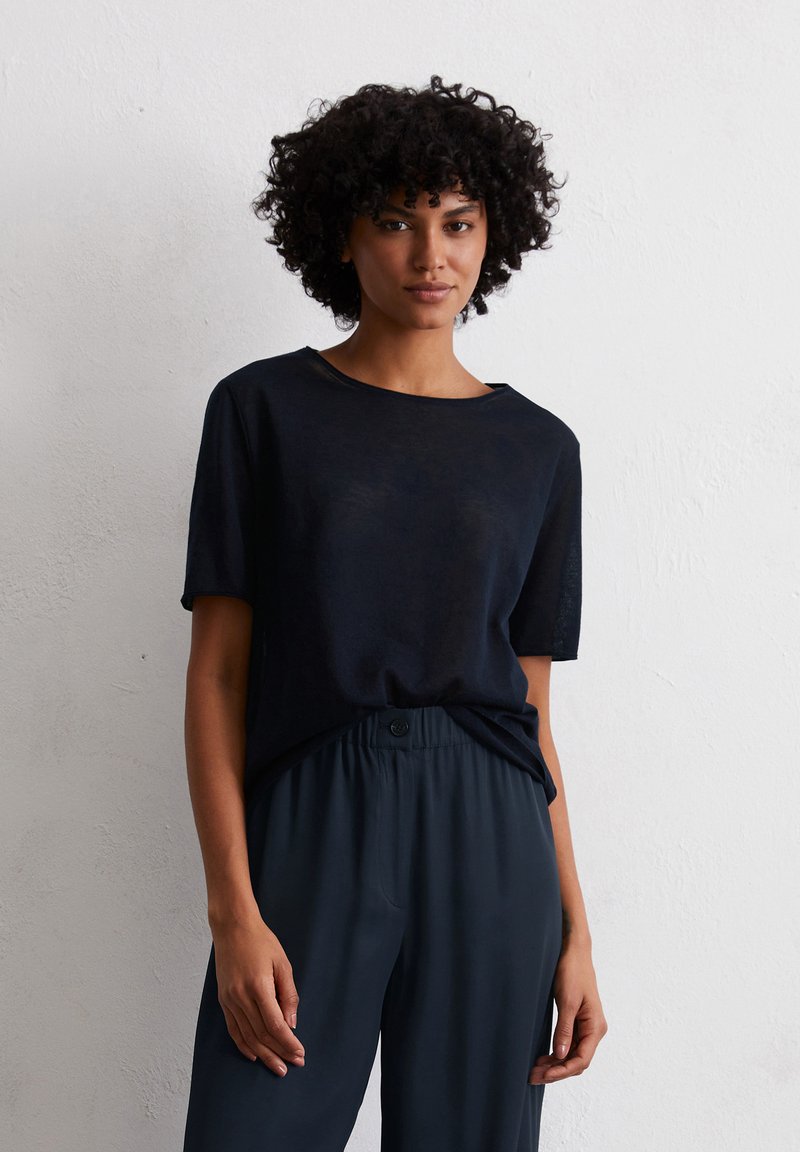 Marineblauwe t-shirt met korte mouwen van een lichtgewicht materiaal, met een relaxte pasvorm en een ronde halslijn, gecombineerd met donkergrijze broek met elastische taille.