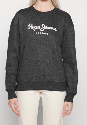 Osoba nosící tmavě šedou mikinu s bílým nápisem "Pepe Jeans London" na hrudi, ve světlých kalhotách.
