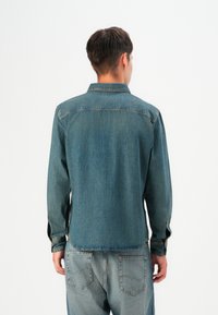 Dunkelblaus Jeanshemd mit langen Ärmeln, Knopfmanschetten und klassischem Kragen. Verfügt über einen geraden Schnitt und eine Rückenpasse.
