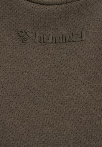 "Hummel logo embossed on textured olive-green fabric, showing brand name and stylized bumblebee emblem."