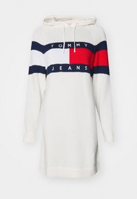 Abito a manica lunga con cappuccio di colore crema, caratterizzato da strisce orizzontali blu navy, rosse e bianche, e con il logo "TOMMY JEANS" sul petto. Texture lavorata a maglia.