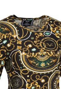 Schwarz gemusterte Bluse mit goldenen Ketten, smaragdgrünen Akzenten und kunstvollen Designs. Runde Halslinie und weiches Textil mit glänzender Oberfläche.