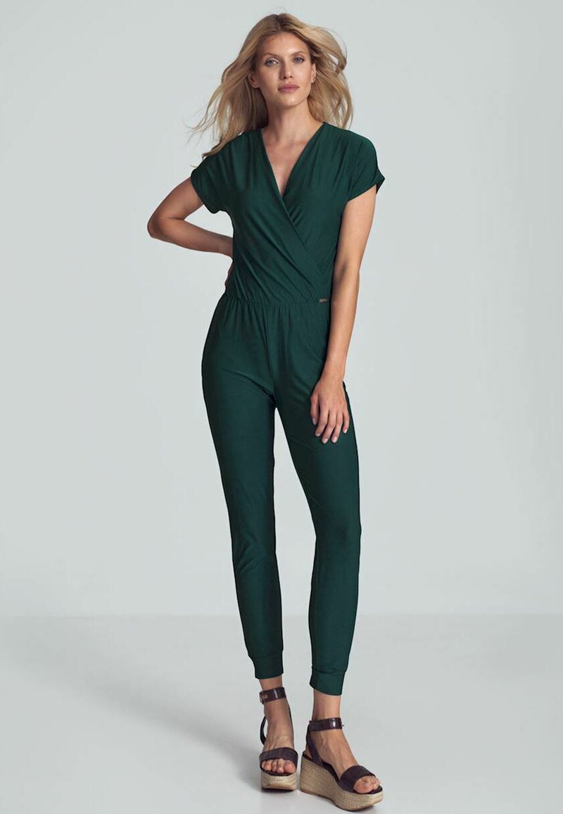 Groene jumpsuit met een wikkelvoorkant, korte mouwen en taperende pijpen. Gecombineerd met bruine sleehakken met enkelbandjes. Nette textuur.