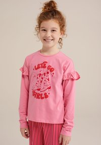 Rožinė ilga rankovė palaidinė su volanėlėmis, su raudonais grafikos tekstais ir riedučio dizainu. Derinama su raudonai-baltomis dryžuotomis kelnių.