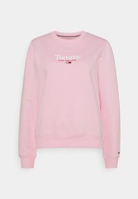 Vaaleanpunainen collegepaita pehmeästä kankaasta, jossa on pyöreä pääntie, pitkät hihat ja valkoinen "Tommy Jeans New York" -logo.