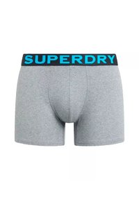 Boxers grises de algodón con una cinturilla elástica azul que presenta el logo "SUPERDRY" de manera prominente. Textura suave, diseño ajustado.