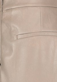 Ljust beige lädertextil med en slät yta, med en horisontell fickdesign och subtila ådringar.