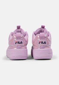 Sneaker rosa con finitura lucida, collare imbottito e dettagli testurizzati. Presenta un linguetta per il tallone e un'etichetta bianca con logo sul tallone.