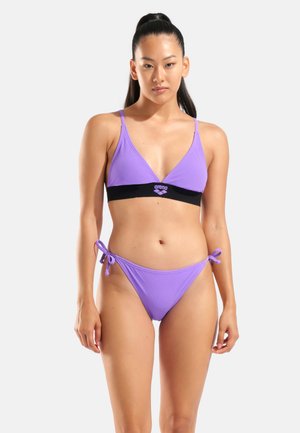 Fialová sada bikin s trojuholníkovým vrškom so čiernym akcentovým pásikom a zodpovedajúcim nízkym spodným dielom so zaväzovaním na bokoch. Hladká textúra, minimalistický dizajn.