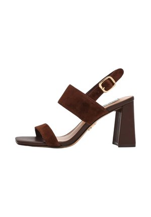 Sandalo aperto in pelle scamosciata marrone con ampie fasce, fibbia dorata regolabile e tacco largo a blocco su sfondo bianco.