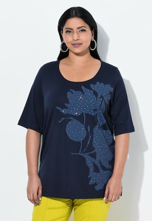 Navy blauwe t-shirt met korte mouwen, voorzien van een bloemdesign met stipaccenten. Gladde stof met een ronde hals, gecombineerd met heldere gele broek.