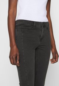 Musta farkkutakki slim fit -mallilla. Ominaisuuksiin kuuluvat etutaskut, vetoketjulukko ja hienovarainen haalistunut rakenne. Vyötäröllä on vyölenkit.