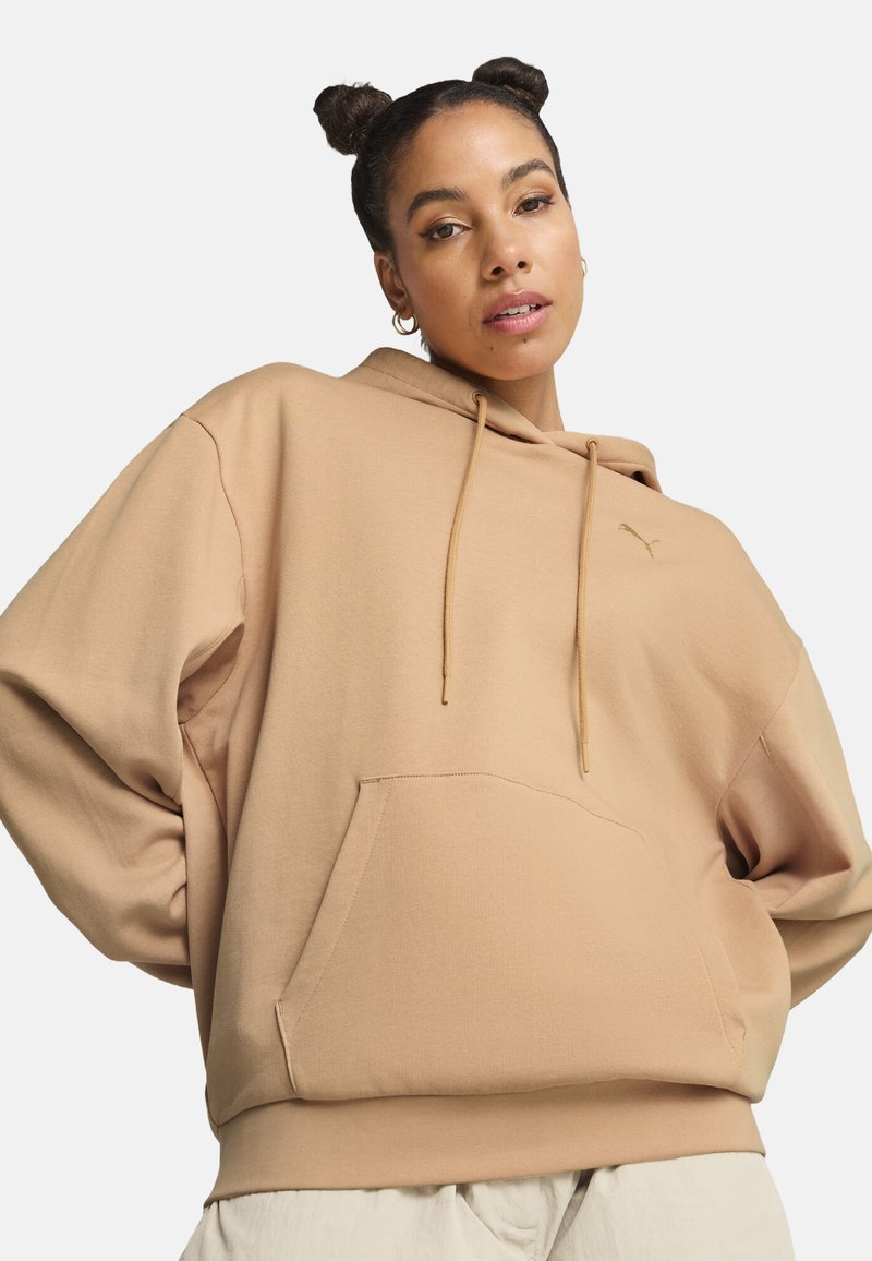 Felpa con cappuccio oversized beige, dotata di tasca a marsupio, cordini e dettaglio logo dorato. Tessuto morbido e vestibilità rilassata.