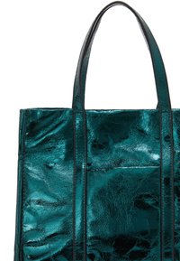 Fémes zöld táska fényes felülettel, téglalap alakú, két erős füllel és elülső zsebbel, sima textúrával.