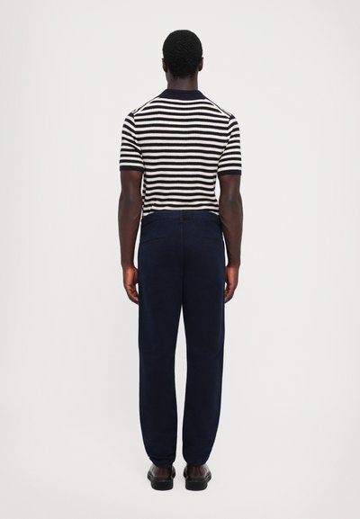 Gestreiftes kurzärmeliges Shirt aus Strick in Marineblau und Creme, kombiniert mit Marineblauen Hosen. Glatte Textur, lässiger Schnitt und klassisches Design.