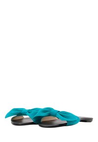 Sandale din suede de culoare teal, cu un detaliu mare sub formă de fundă, având o talpă plată neagră și o branț texturat.