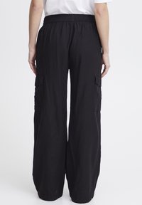 Pantalons cargo noirs avec une coupe décontractée, taille élastique, deux poches latérales et un tissu doux et texturé pour le confort et la liberté de mouvement.