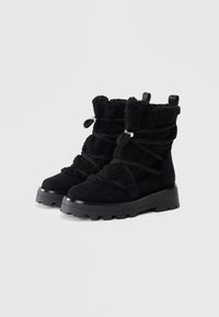 Botas negras hasta el tobillo con un upper suave y texturizado, detalles de cordones y suela de goma con tracción estriada para un buen agarre.