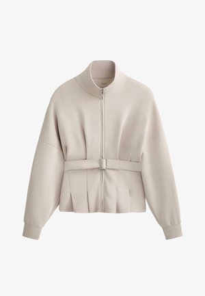 Veste zippée beige clair avec un col haut, des manches larges et une taille ceinturée. Présente des détails de design plissés et une texture de tissu douce.