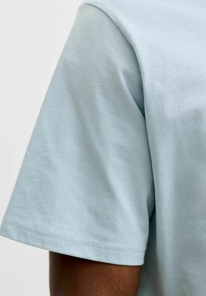 Lyseblå T-shirt med korte ærmer lavet af blød bomuld. Har en rund halsudskæring og simpel kantning uden mønstre eller accenter.