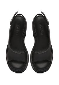 Zwarte leren slingback sandalen met open tenen, een gladde textuur, gebogen ontwerp en stikselafwerking langs de randen. Gesp sluiting bij de hak.