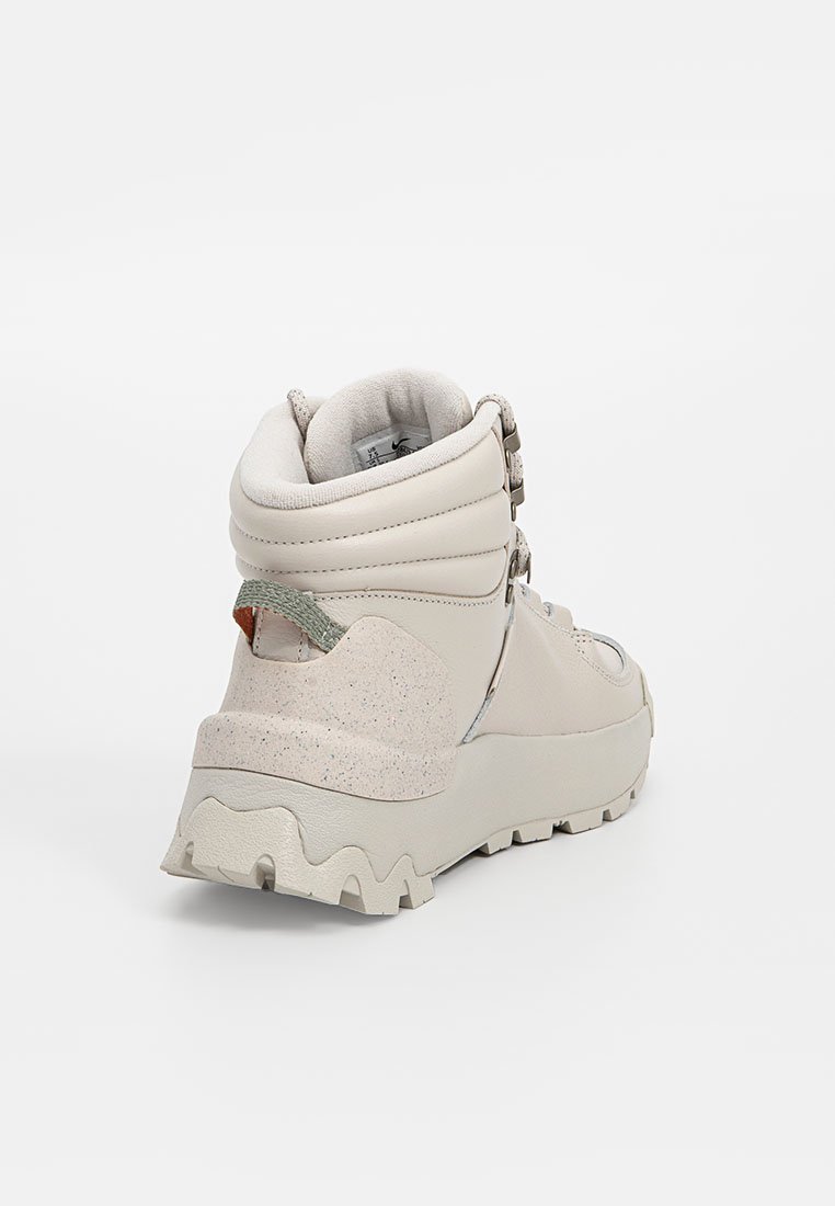 Bota de senderismo de caña alta en color beis, con un acabado texturizado, material de cuero duradero y una suela de goma gruesa con patrones de tracción pronunciados.