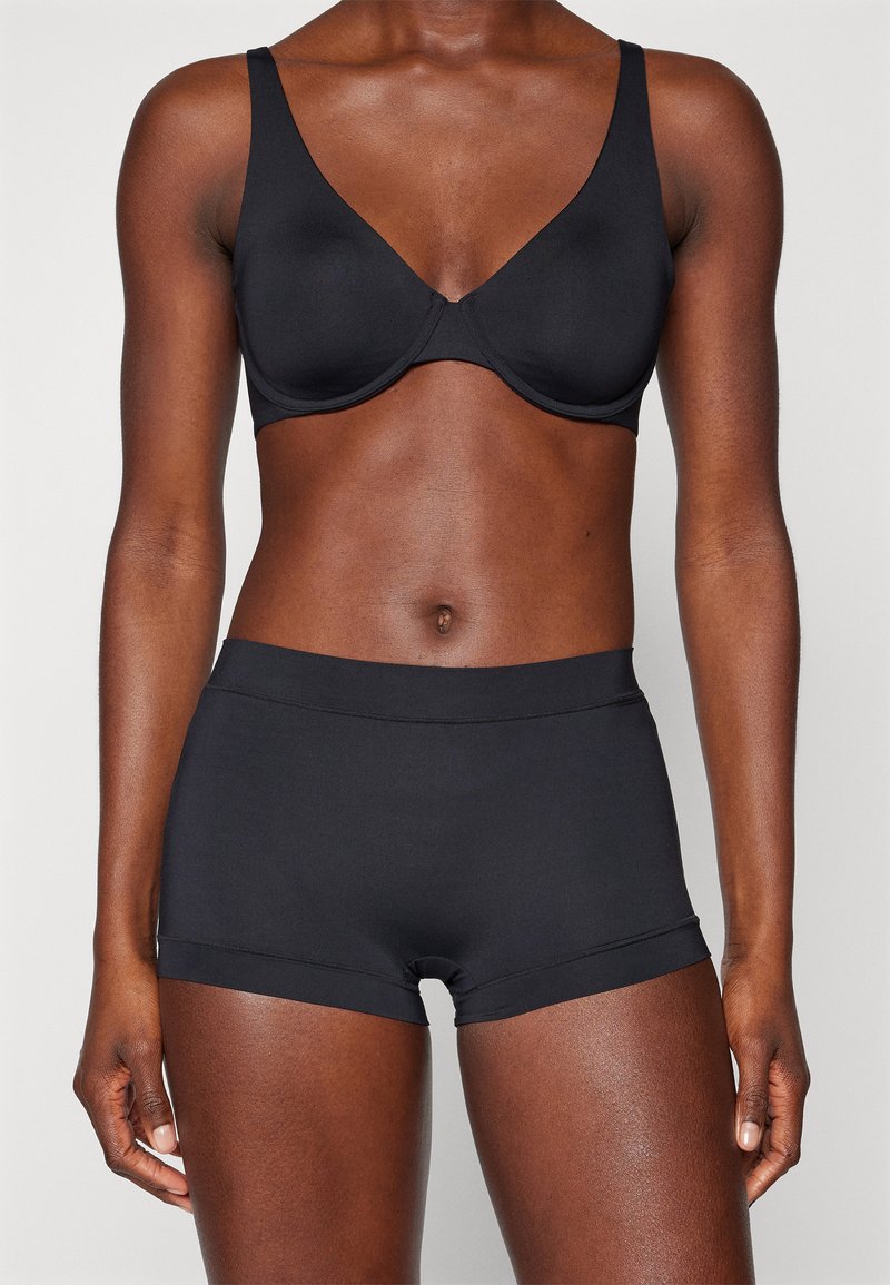 Black bra with smooth cups and wide straps, paired with matching black shorts featuring a seamless design and soft texture.