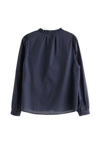 Tmavě modrá halenka s dlouhým rukávem, drobné červené puntíky, volánový límec, rukávy na knoflíky a volný střih, vyrobená z lehké látky.