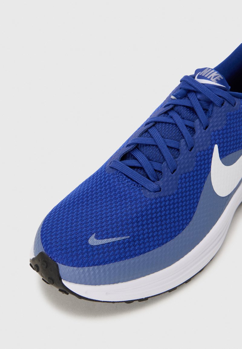Zapatilla de correr de malla azul con una superficie texturizada, logo de swoosh blanco y acentos en azul claro contrastantes. Presenta una suela de goma negra.