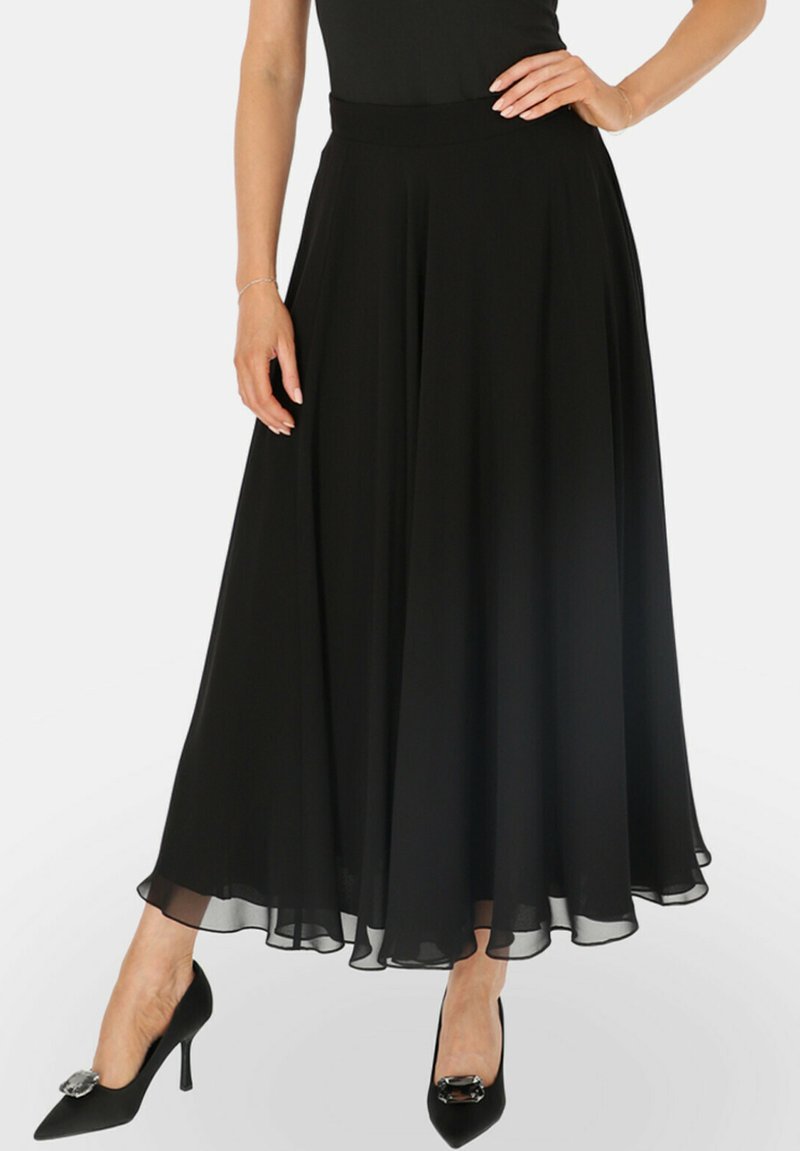 Czarna, zwiewna spódnica maxi z dopasowanym paskiem w talii oraz warstwową, przezroczystą teksturą. Połączona z czarnymi, spiczastymi szpilkami z srebrnym akcentem.