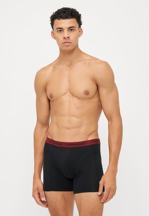 Schwarze Boxer-Briefs mit einem bordeauxroten elastischen Bund, der das Logo "BJÖRN BORG" trägt. Der Stoff wirkt weich und sitzt eng. Schlichte Gestaltung.
