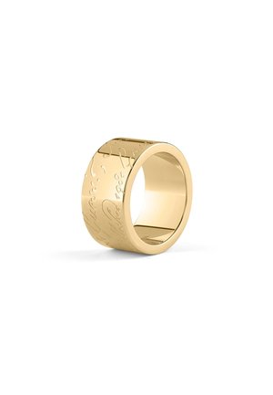 Large bague en or avec une inscription en écriture cursive gravée sur la surface extérieure, présentée sur fond blanc.