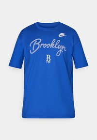 Mėlynas medvilnės marškinėliai su užrašu "Brooklyn" baltu šriftu, Nike logotipas ant peties ir glotnia tekstūra su trumpomis rankovėmis.