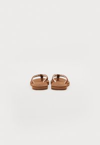 Brown flip-flops with a thin strap design, featuring a textured footbed and a light-colored sole. Logo visible on the footbed.