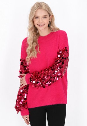Fluffy felroze sweater met lange mouwen versierd met glanzende rode pailletten. De stof heeft een zachte textuur en biedt een losse pasvorm.