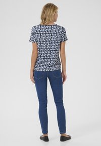 Korte mouwen zwart en lichtblauw geblokt blouse met een ronde halslijn en een losse pasvorm, gecombineerd met slim-fit blauwe jeans en zwarte flats.