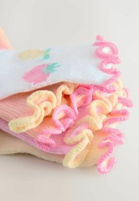 Farverige sokker med pastelnuancer af pink, gul og hvid, med bølgede kanter og legende frugt mønstre, herunder ananas.