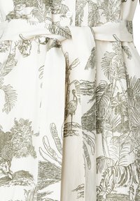 Robe en tissu blanc ornée d'un motif tropical vert avec des feuilles de palmier et de la faune, incluant un pélican et un tigre, cintrée à la taille.