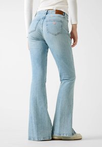 Φαρδιά τζιν παντελόνια σε ανοιχτό μπλε, κατασκευασμένα από τζιν ύφασμα, με μέση μέτριας ανόδου, πέντε τσέπες και ένα καφέ δερμάτινο πίσω ταμπελάκι με λεπτομέρεια λογότυπου.