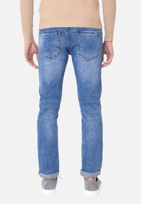 Jeans in denim azzurro chiaro con una vestibilità affusolata, orli arrotolati e cuciture a contrasto. Presentano due tasche posteriori e una texture liscia.