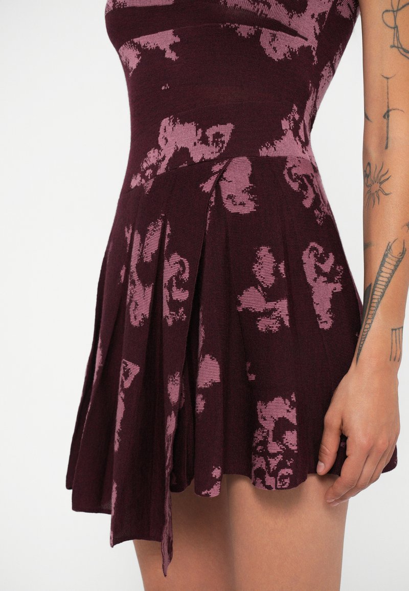 Borgundress med rosa blommönster, åtsittande överdel, utsvängd plisserad kjol. Mjuk textur, knälång, med en sidodetalj med knytning.